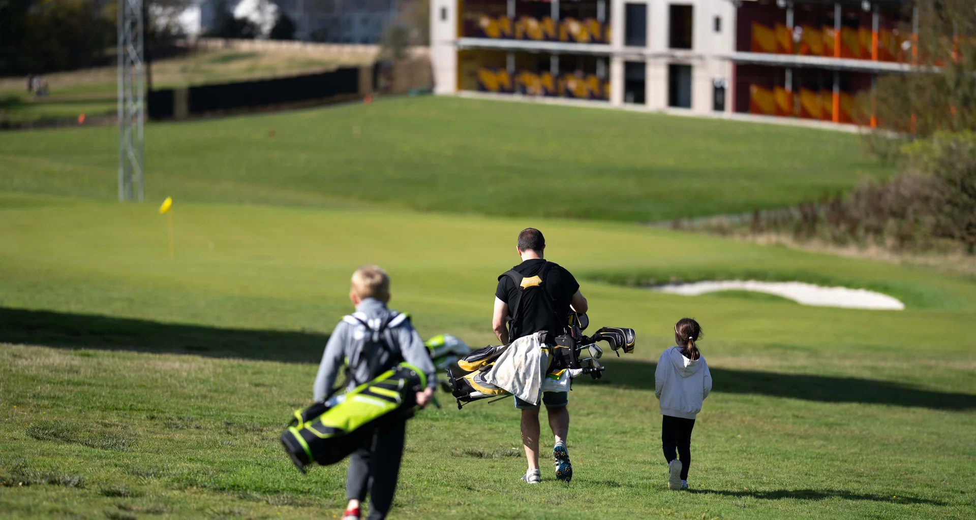A man and two children playing golf at Golf It!