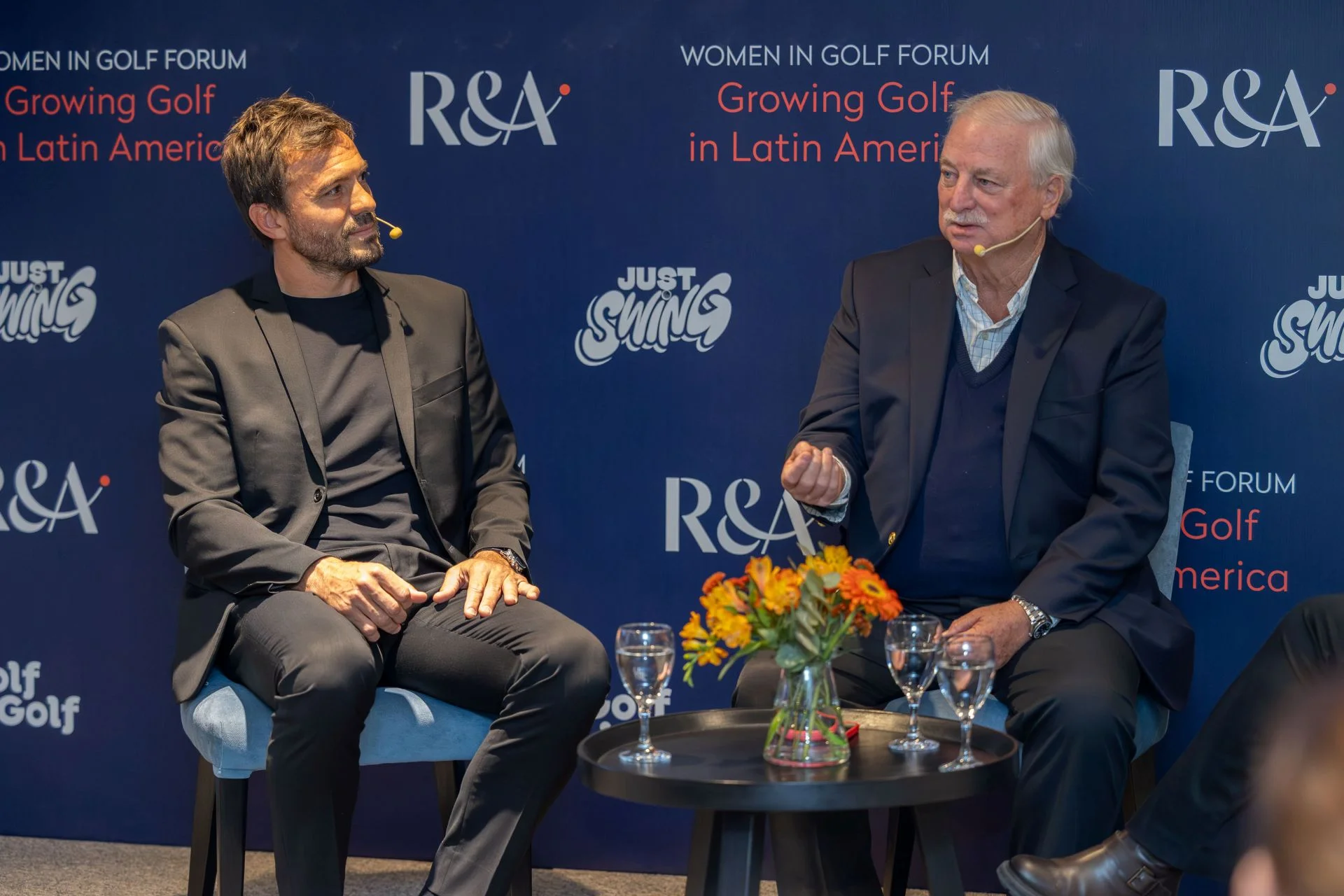 Two men sit beside each other on stage in discussion.
