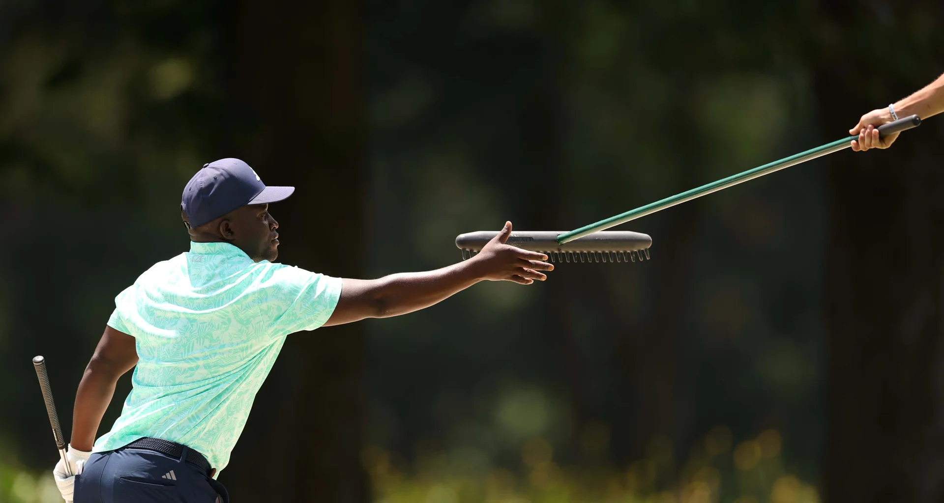 Elton Dancel Zulu of Zimbabwe is passed a rake during Day One of The Africa Amateur Championship at Royal Johannesburg.