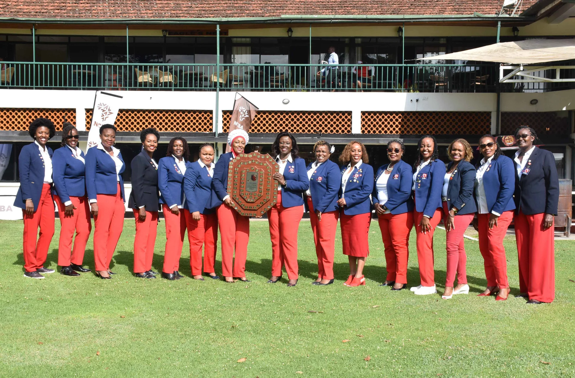 The committee of the Kenya Ladies Golf Union stand together in a line in front of their clubhouse.
