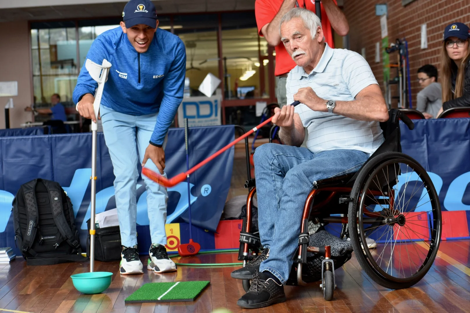 A man in a wheelchair is given golfing tips from an instructor.