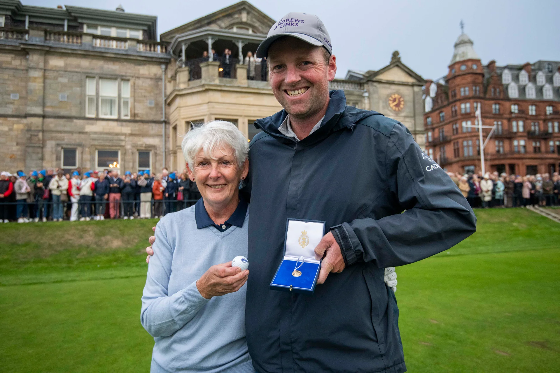 Claire Dowling with Caddie Dillon McCarron, who returned her ball. They stand in front of The Royal and Ancient Clubhouse.
