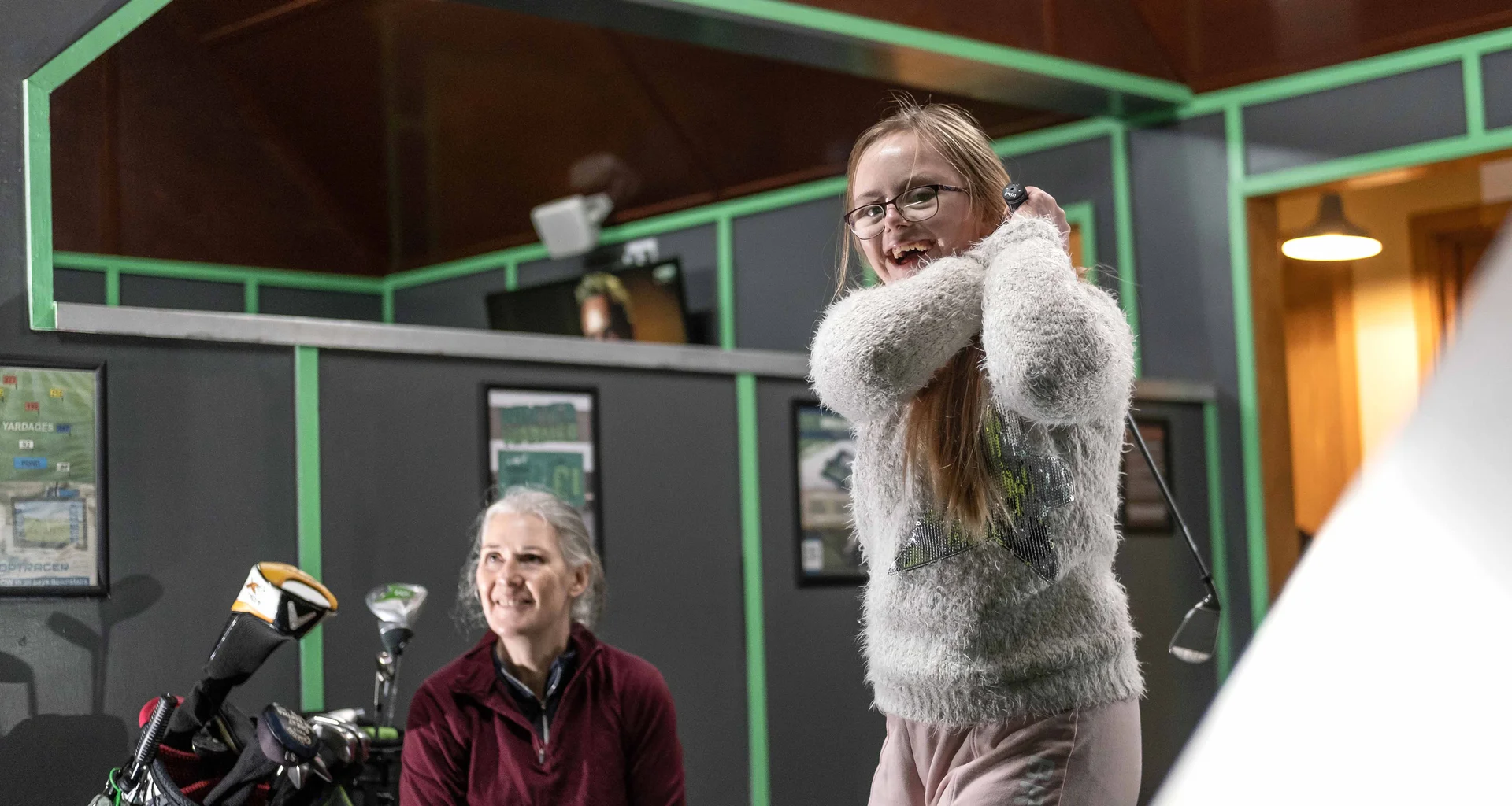 A young girl playing golf at a driving range.