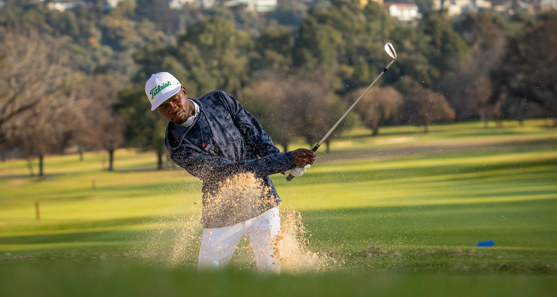 Michael Chuma from Zambia playing a golf shot out of a bunker.