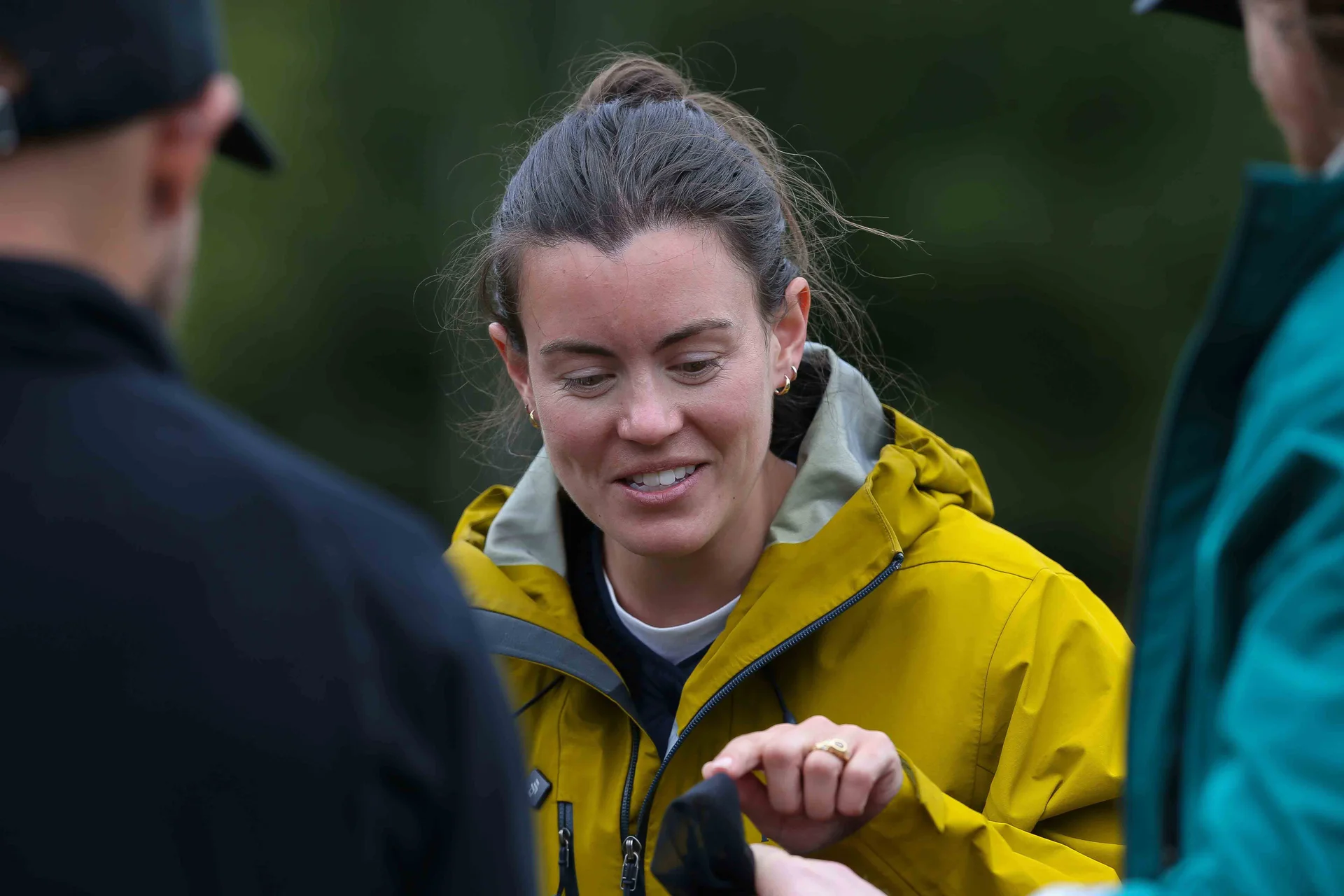 Sophie Olejnik smiles as she talks and points to something held by a man and a women.