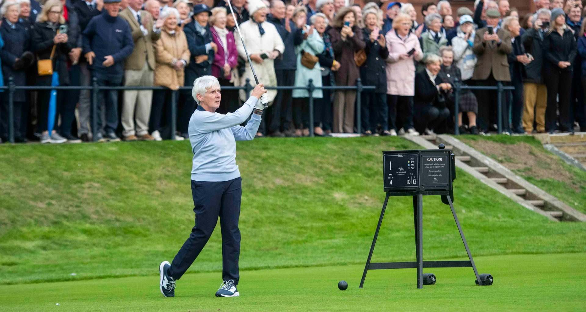 Claire Dowling hits her first tee shot as captain of The Royal and Ancient Club of St Andrews as a crowd of people watch on.
