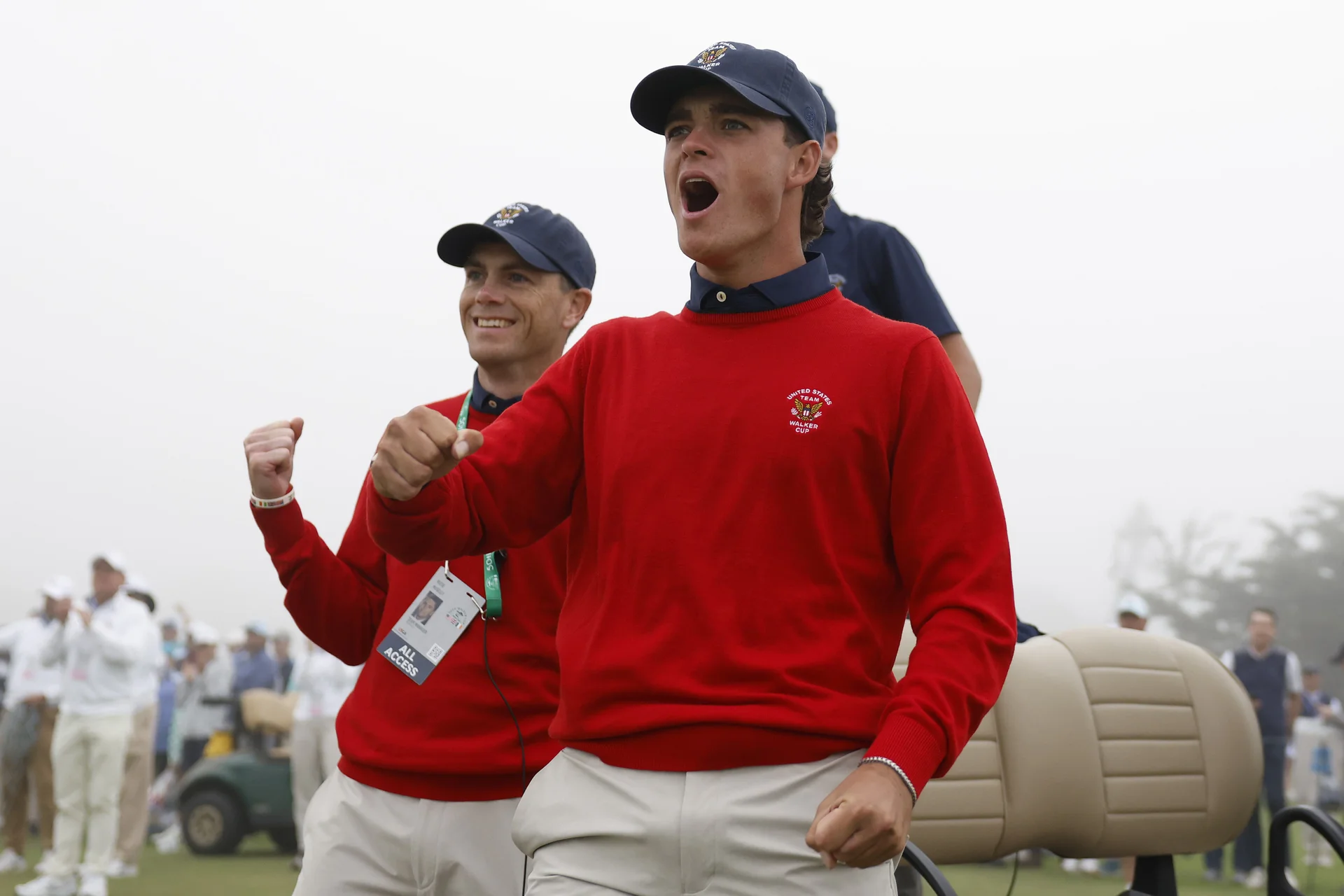 Two men in red sweaters wearing nave caps smiling and raising their fists in celebration.