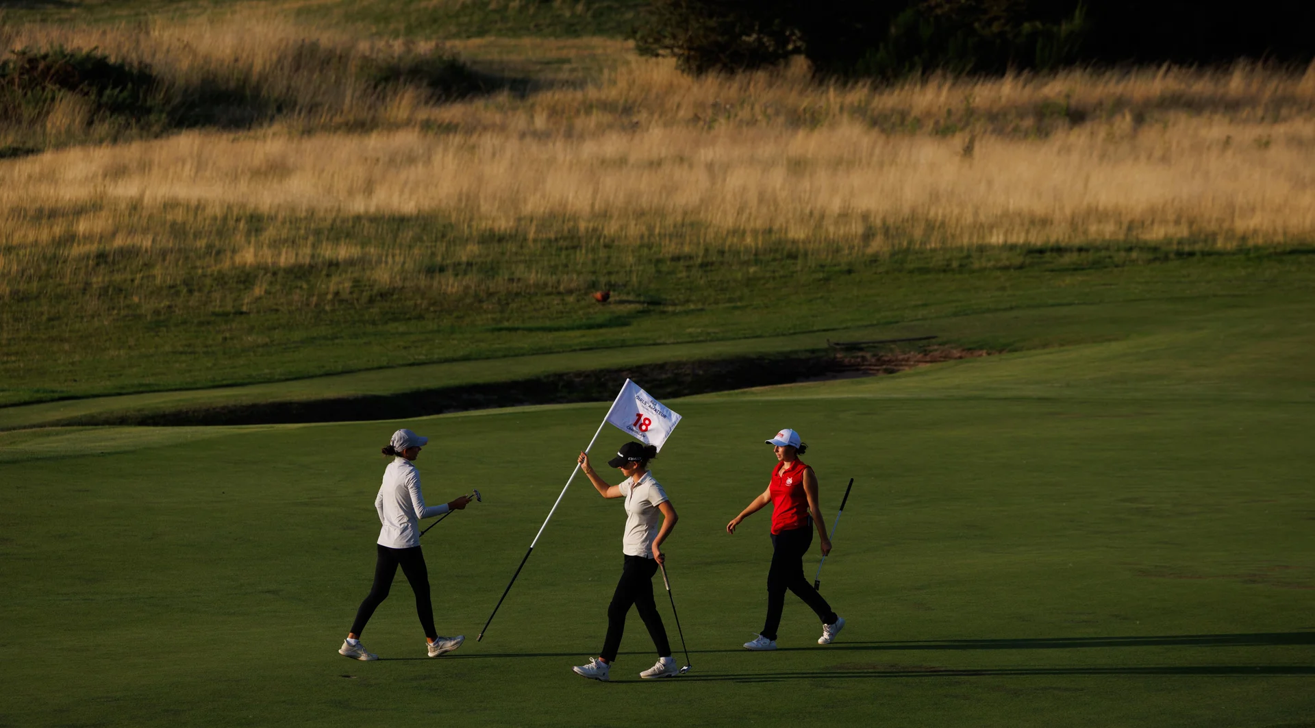 Florence Laforgue of France (L), Summer Carash of England (C) and Vaya Georgieva of Bulgaria on the 18th green during Day One of the R&A Girls' Amateur Championship.