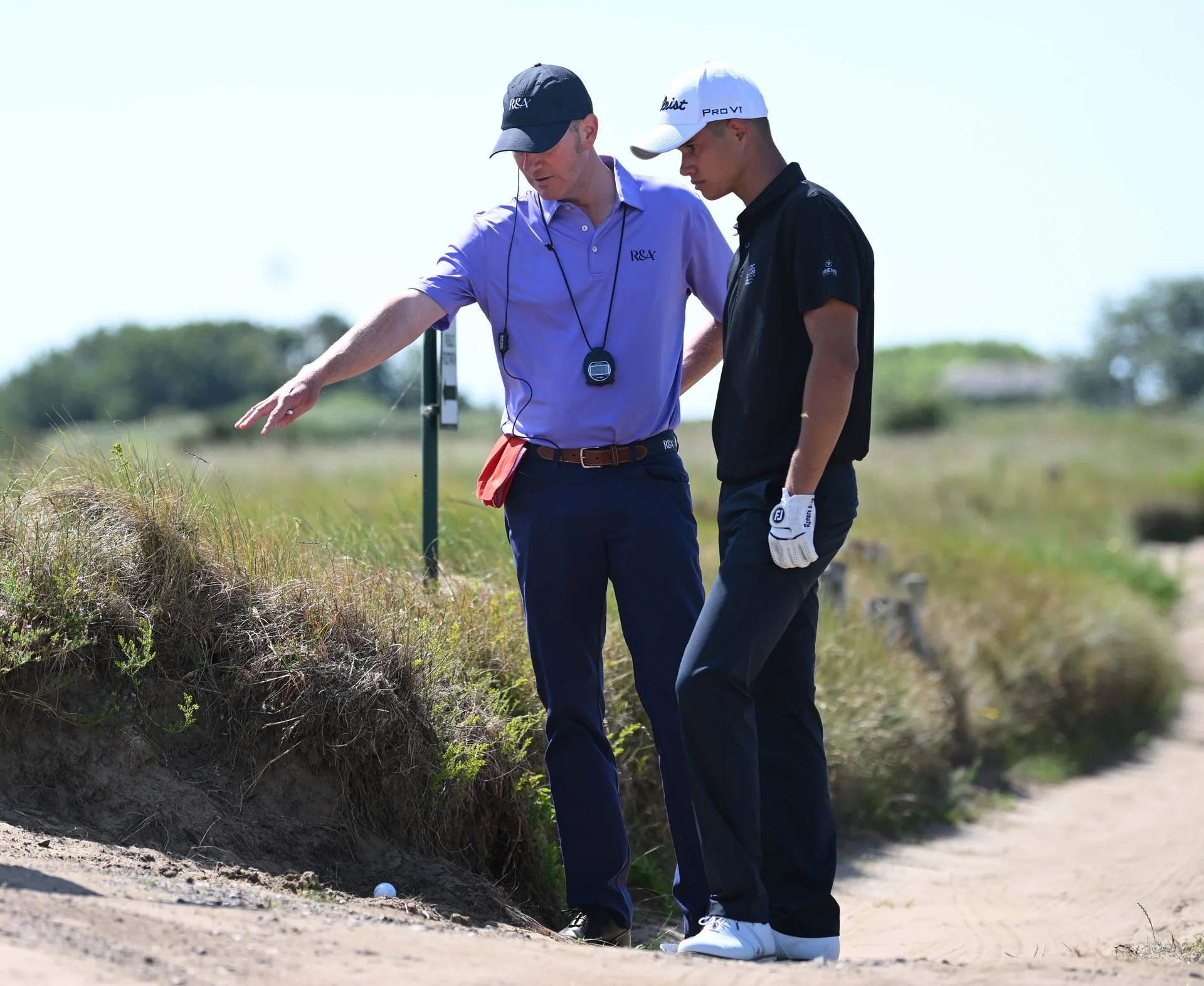 An R&A rules official in conversation with a golfer while standing in a bunker.