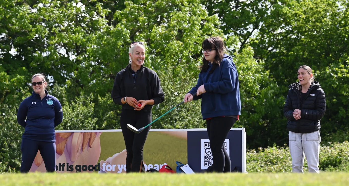An instructor guides a teenage girl during a golf session at The G4D Open.