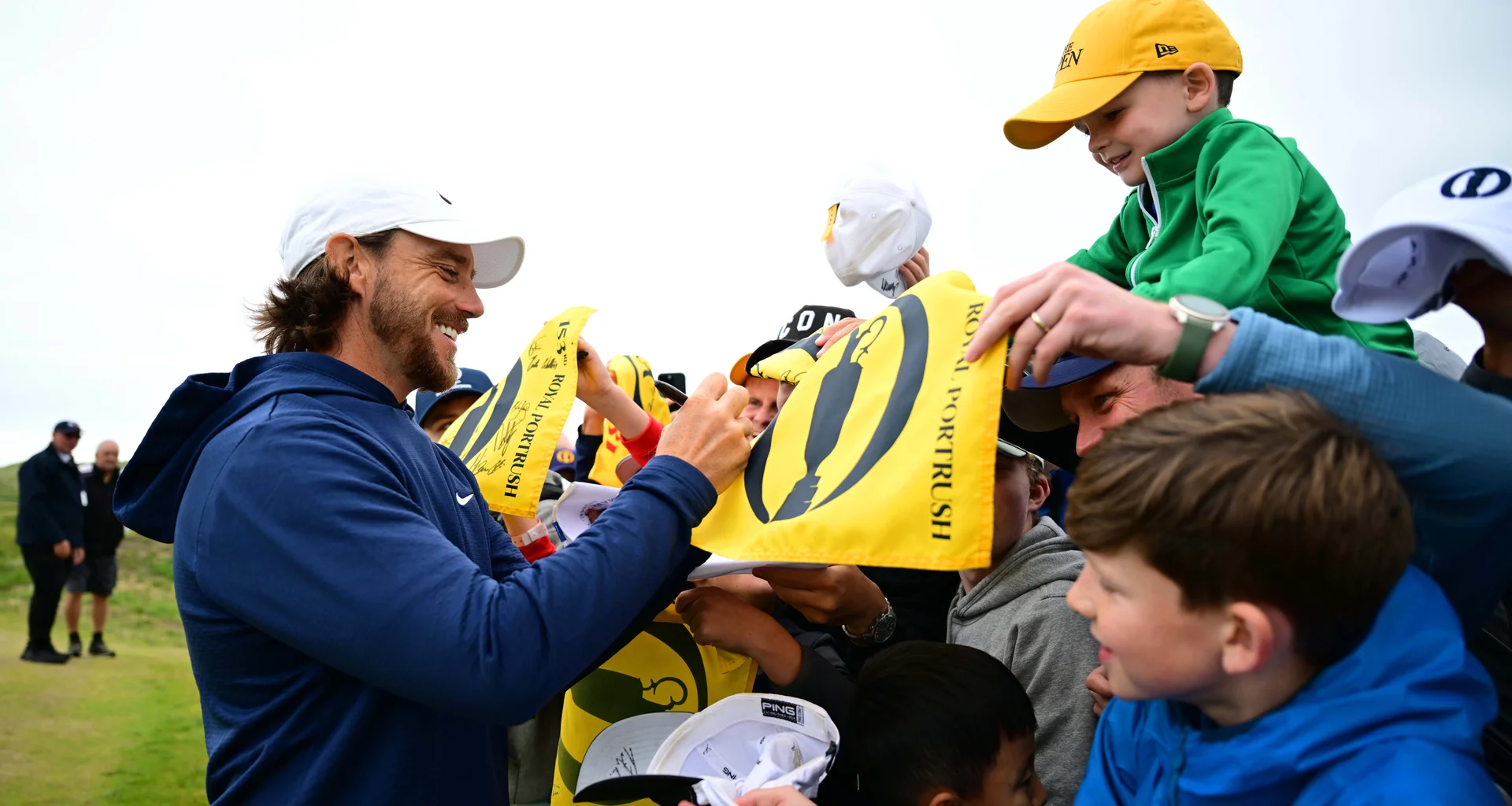 Tommy Fleetwood meets spectators at The Open and signs a pin flag for a young fan.