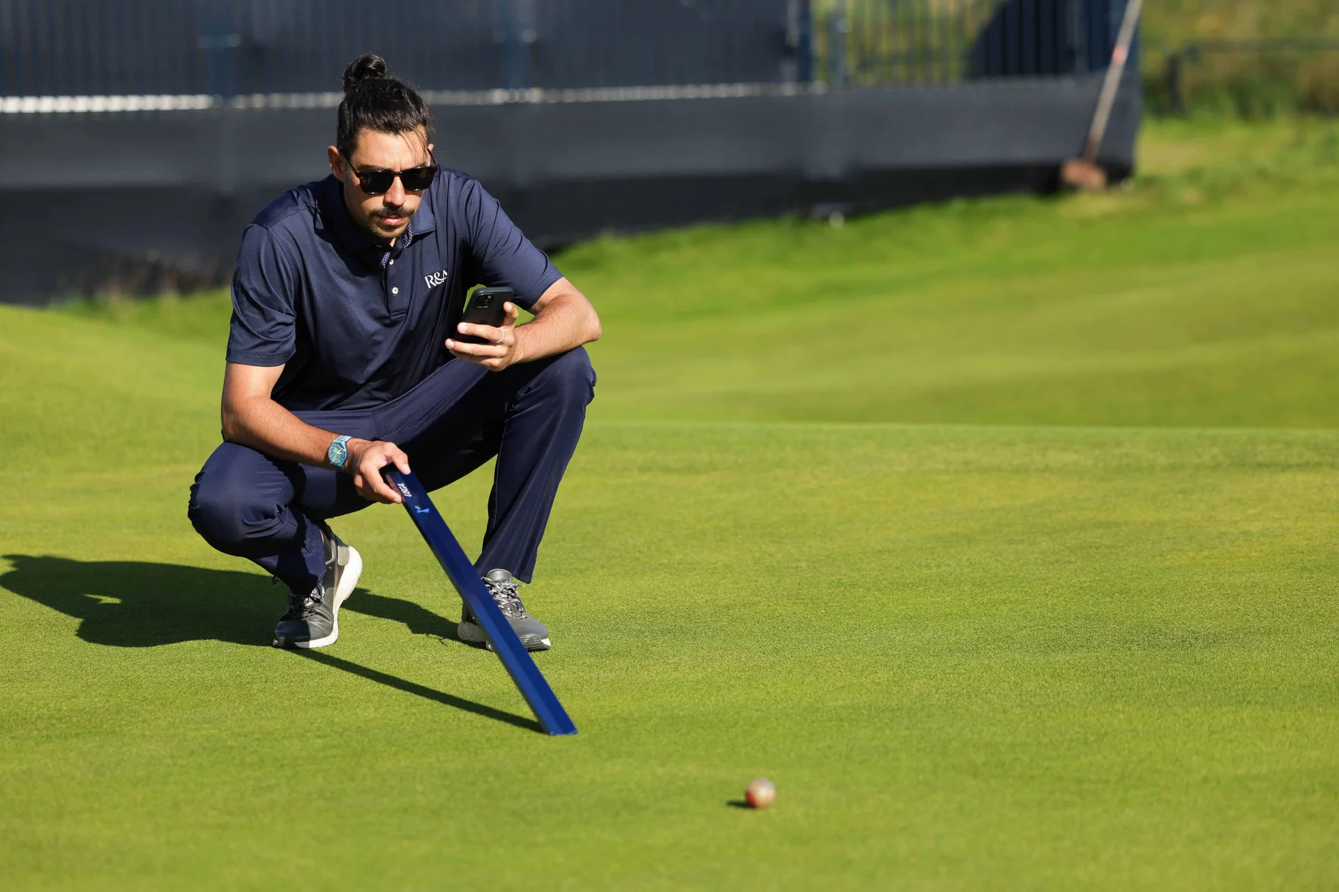 An agronomist from The R&A takes measurements on a golf green.