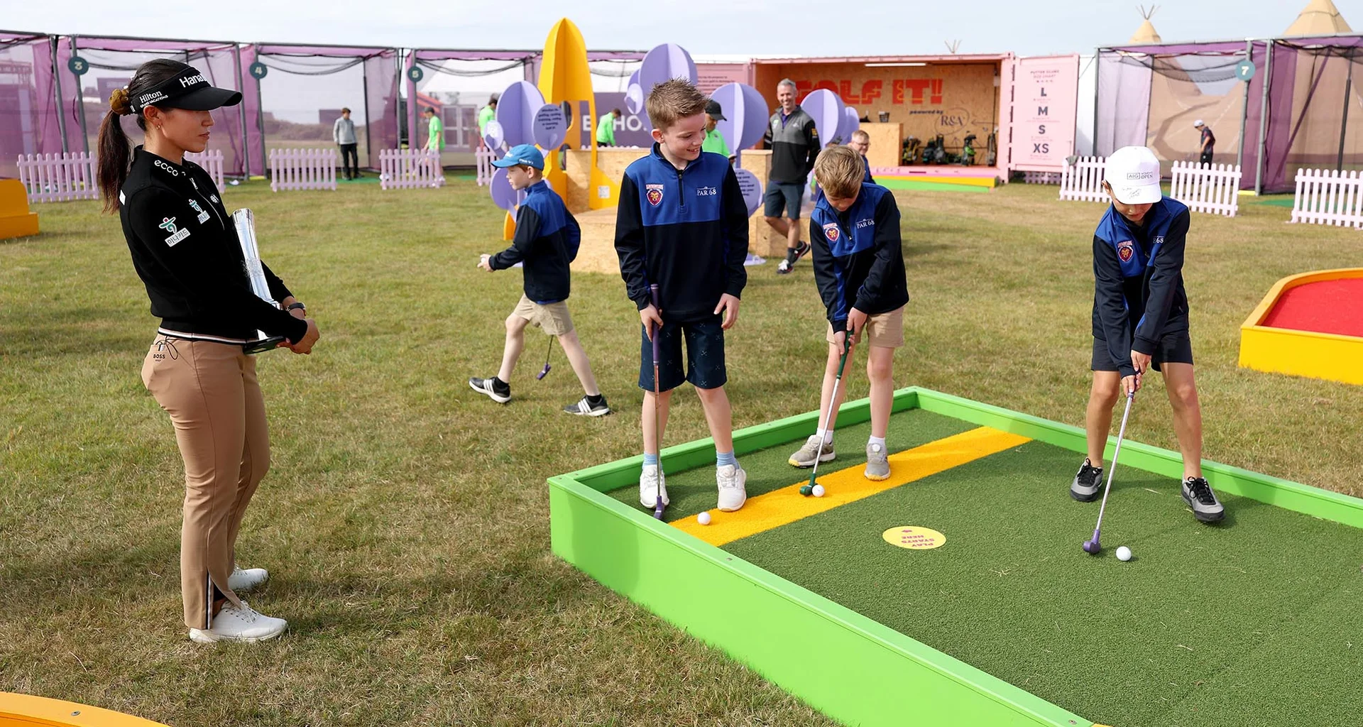Lydia Ko of New Zealand watches on as children take part in the R&A 'Golf It' initiative prior to the AIG Women's Open 2025 at Royal Porthcawl Golf Club.