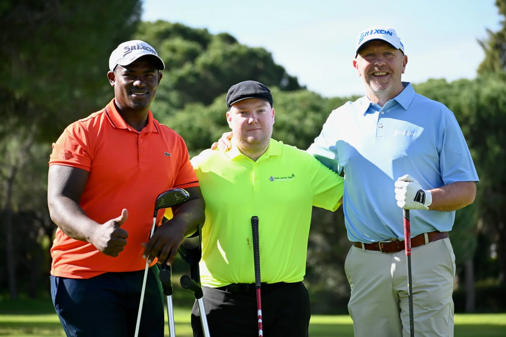 Three golfers with disabilities stand arm-in-arm smiling.