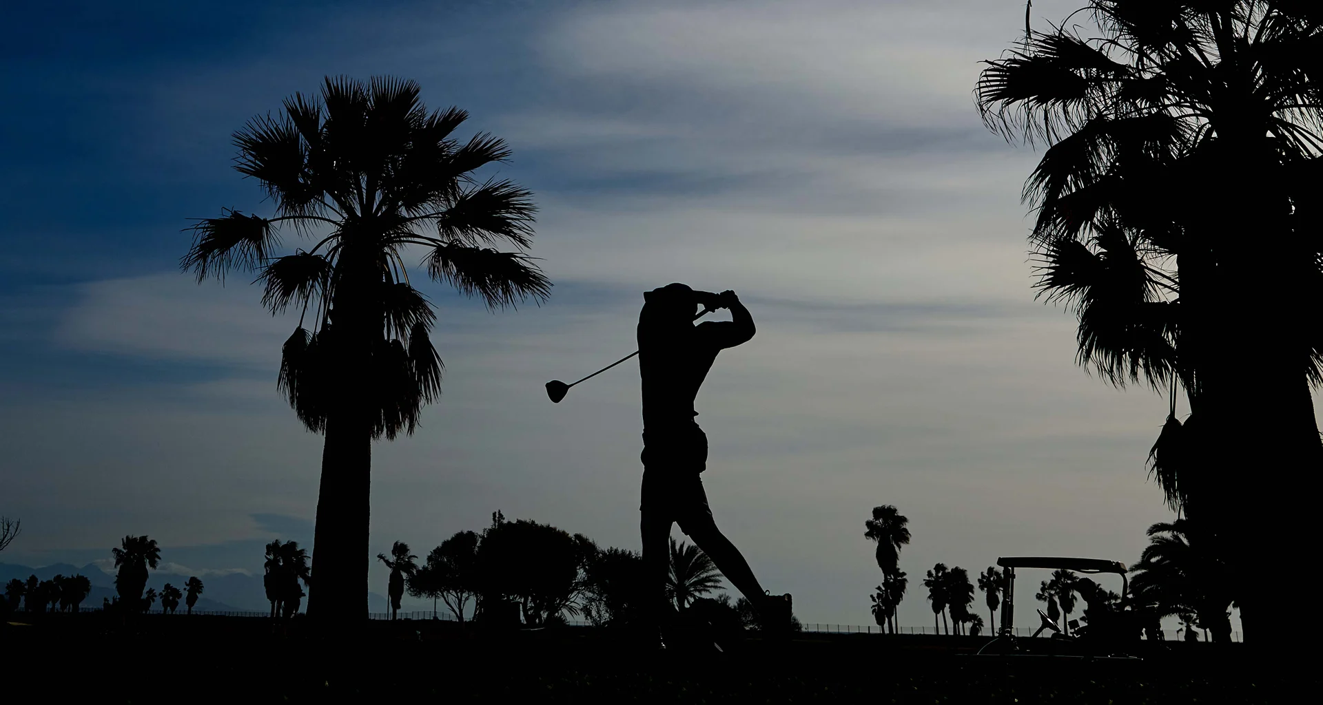 A golfer takes a swing.