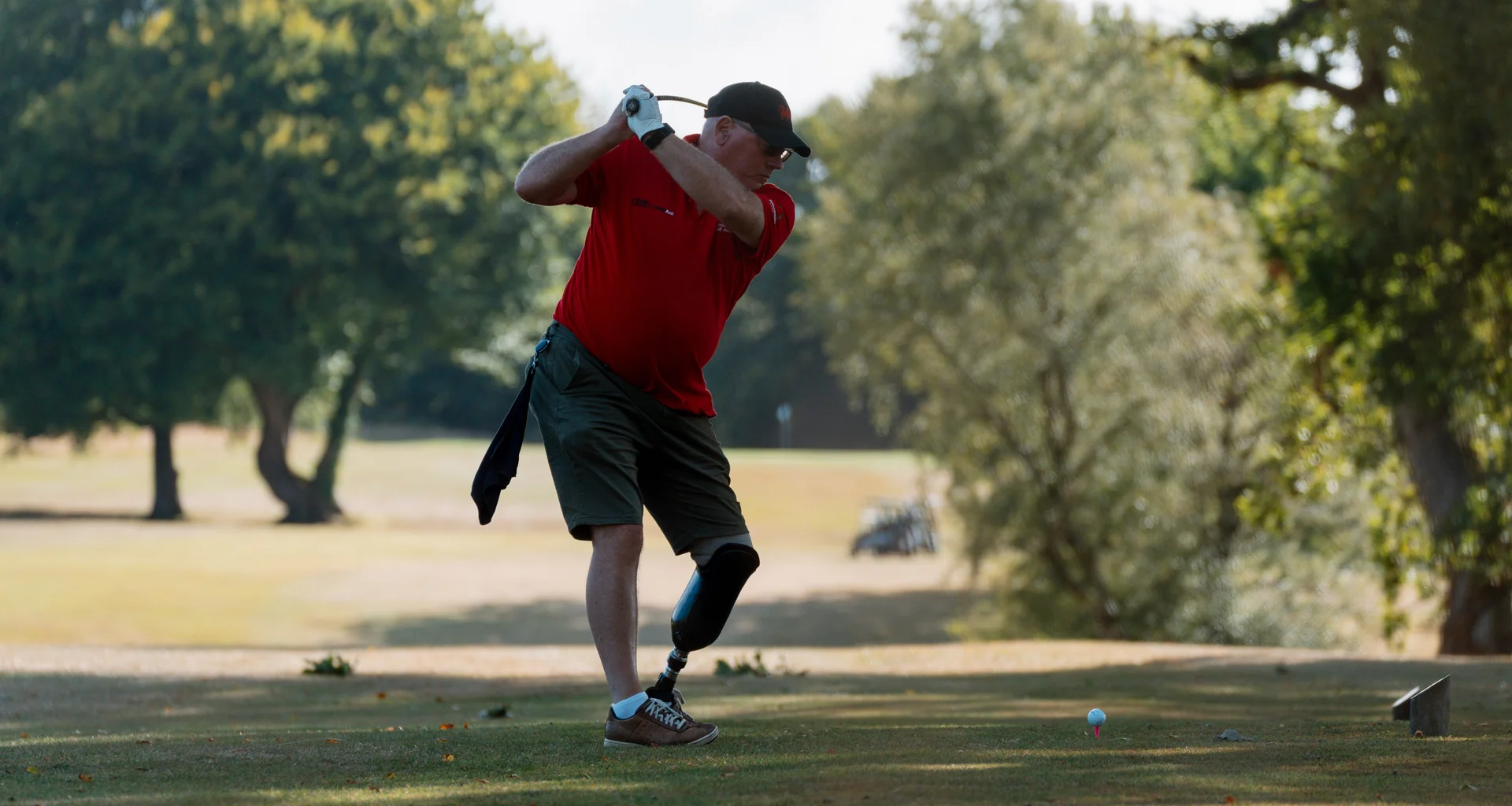 A golfer with a leg amputation plays a tee shot.