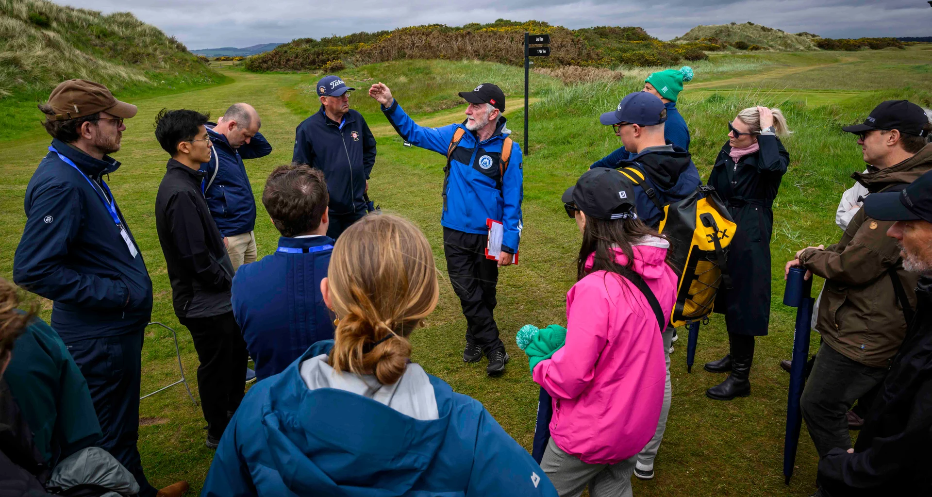 A man shows a group of people around a golf course on a nature trail.