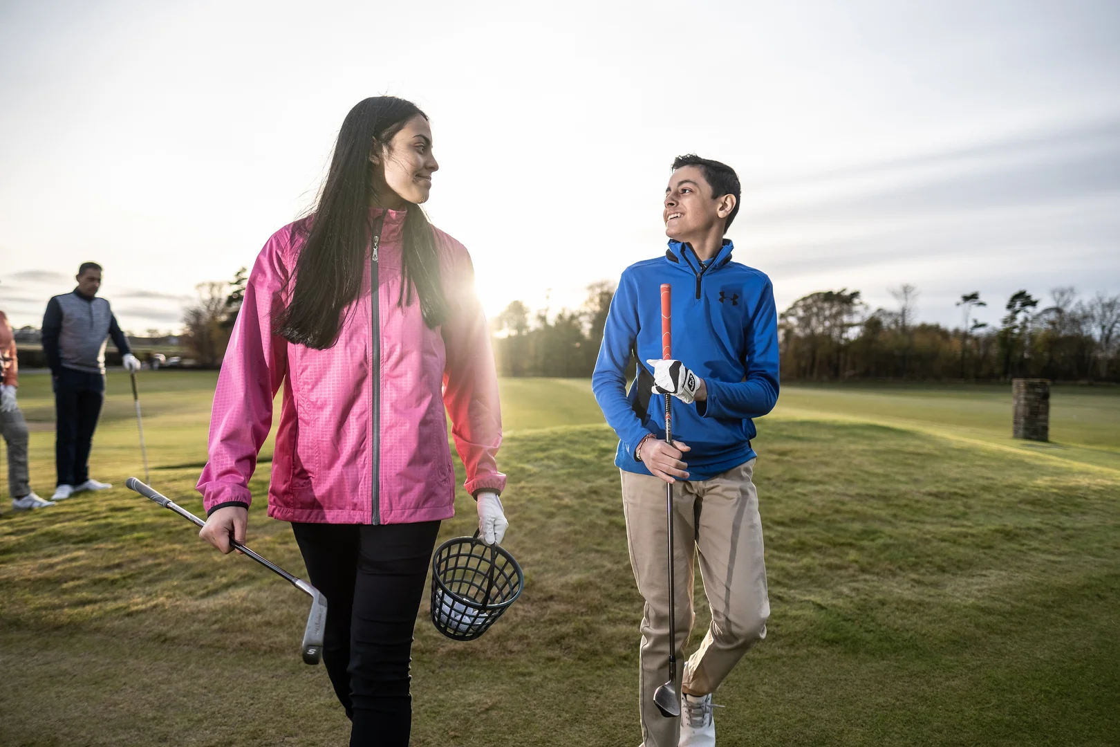 Two junior golfers on a driving range.