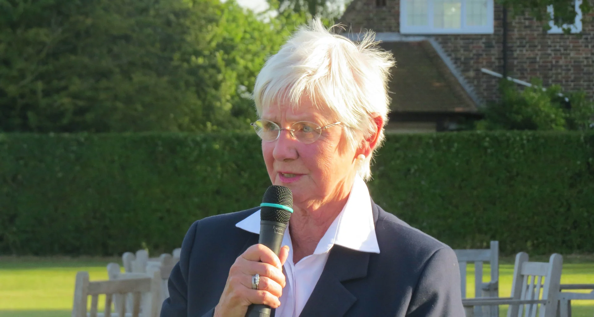 A portrait image of Brigid McCaw who is holding a microphone up to her mouth.
