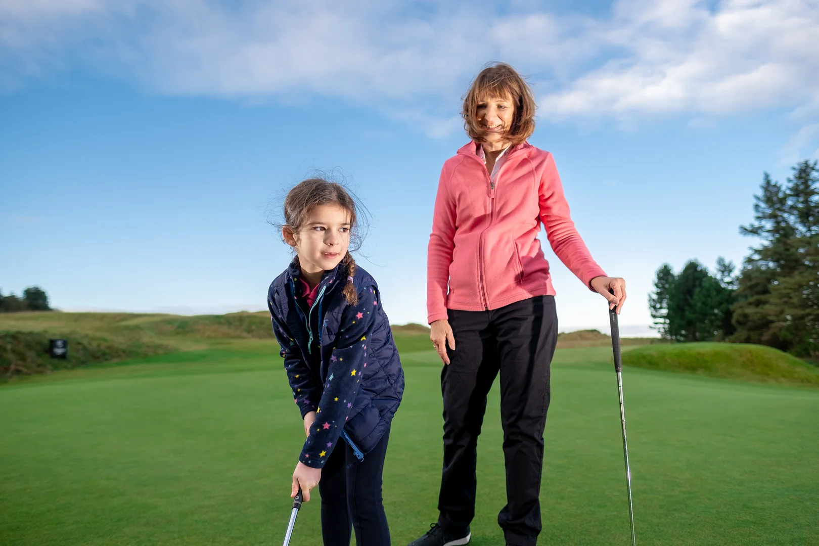 women and girl on a golf course